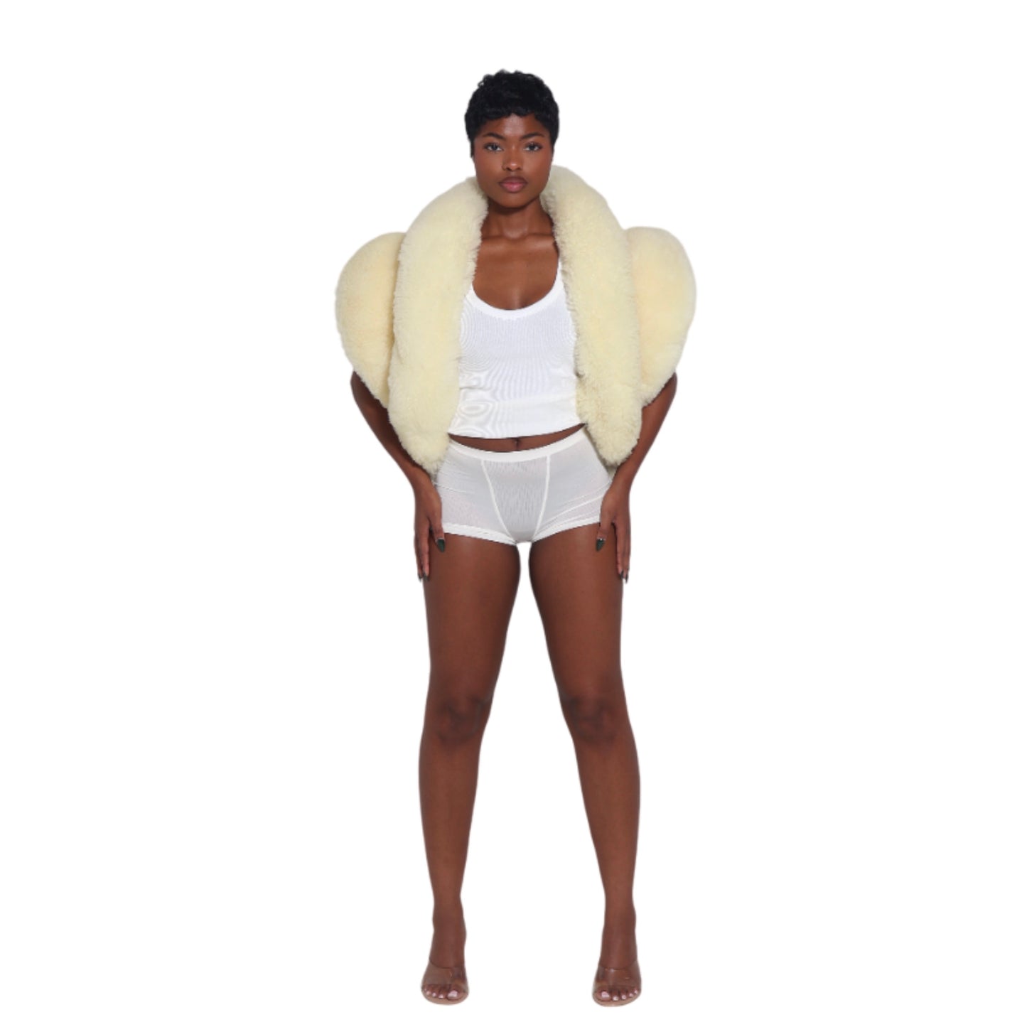 woman wearing a pale yellow shearling vest over a white tank top and shorts standing on a white background